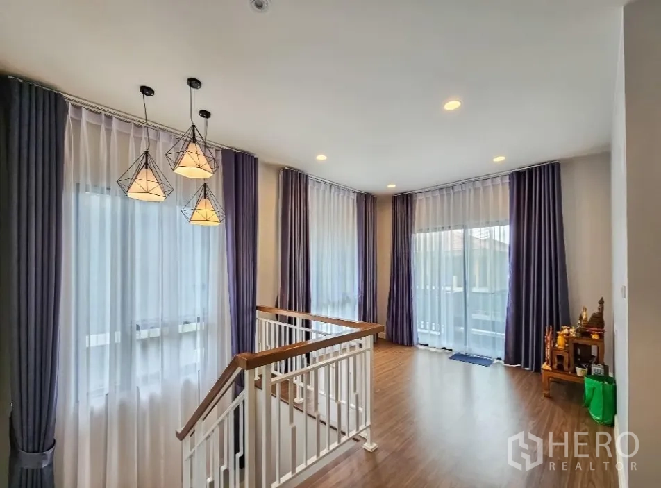 Detached House for sale in Lam Luk Ka, Pathum Thani - Upstairs landing with geometric pendant lights, wood floors and balcony access.