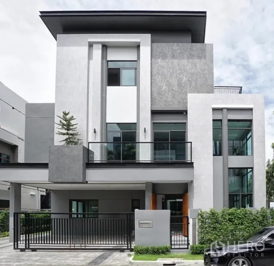 独立式住宅 出租或出售在Phra Khanong, Bangkok - 三层现代独栋别墅外立面，带阳台、大窗与带门车位。