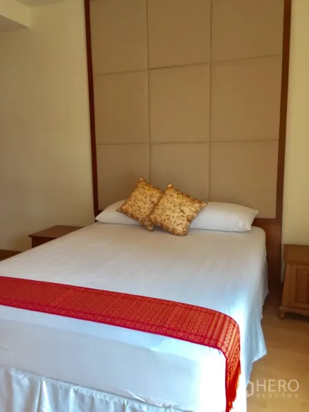 Condominium for rent in Khlong Toei, Bangkok - Cozy second bedroom with upholstered headboard and queen bed with red runner.