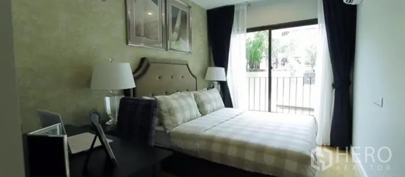 Condominium for rent in Khlong Toei, Bangkok - Cozy bedroom with upholstered headboard, desk, and a large window leading to the balcony.