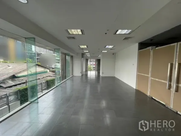Office Space for rent - Open-plan office with floor-to-ceiling glass windows, gray tiled floor, and drop-ceiling lights.