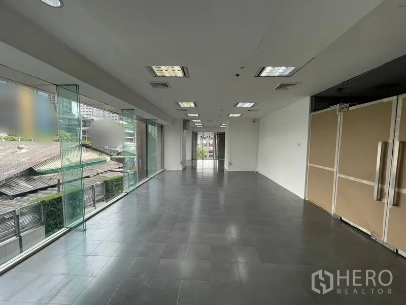 Office Space for rent - Open-plan office with floor-to-ceiling glass windows, gray tiled floor, and drop-ceiling lights.