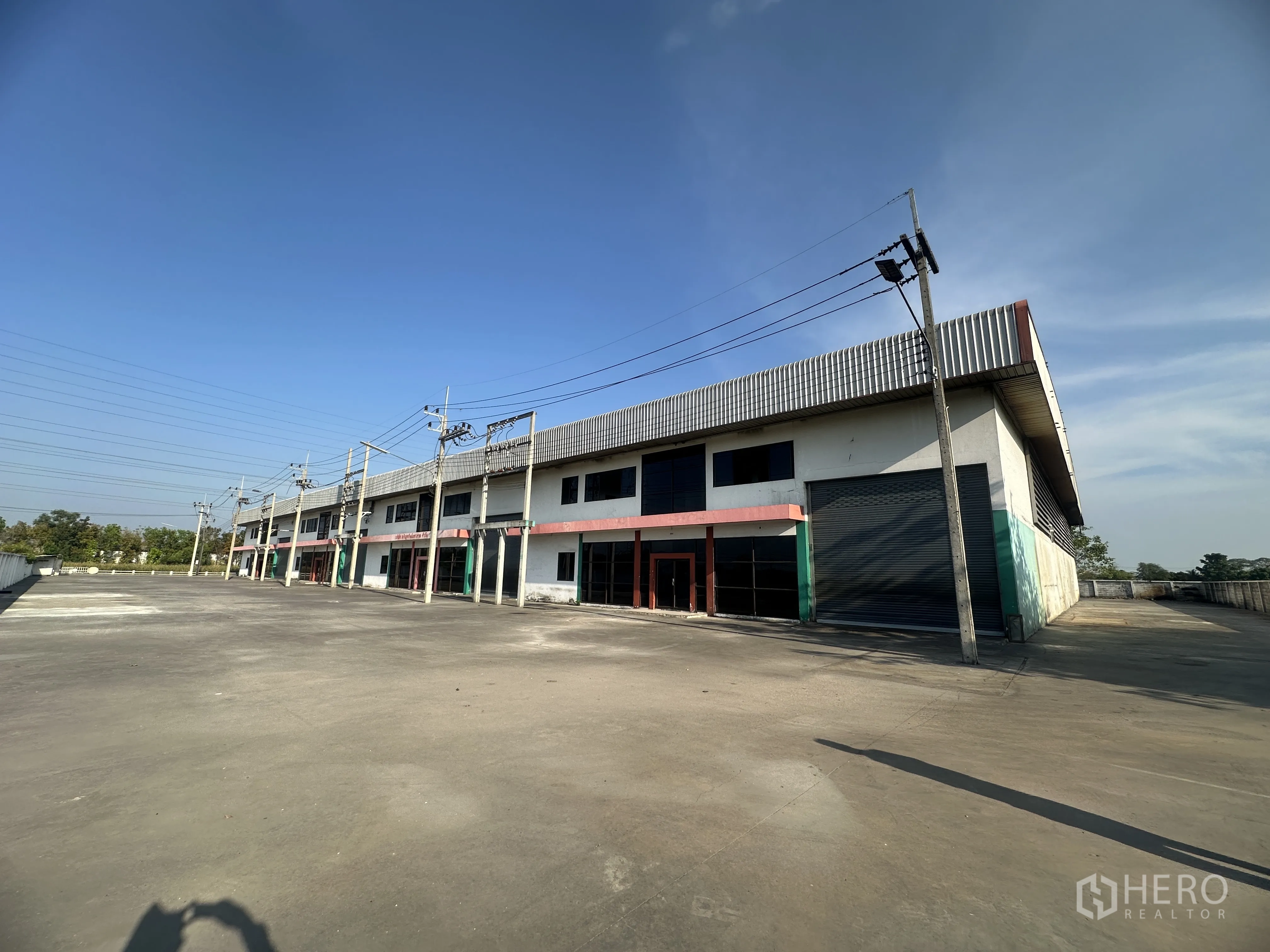 Factory for rent in Wang Noi, Phra Nakhon Si Ayutthaya - Perspective of multiple factory units with glass frontages, roller doors, and an expansive yard.