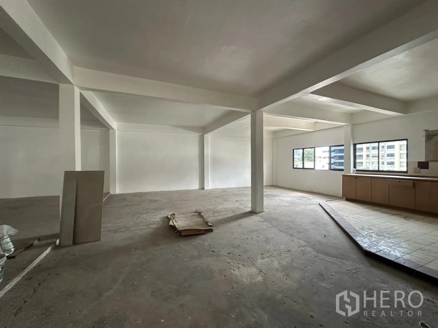零售空间 for rent in Watthana, Bangkok - 明亮的开放零售空间，数扇窗户以及位于瓷砖平台上的内置柜体。