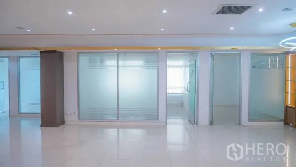 Office Space for rent in Chatuchak, Bangkok - Open workspace with large frosted‑glass panels, glass doors, and natural light through blinds.