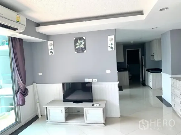 Condominium for rent in Khlong Toei, Bangkok - Living room with TV console, recessed ceiling lights and open-plan flow to the kitchen.