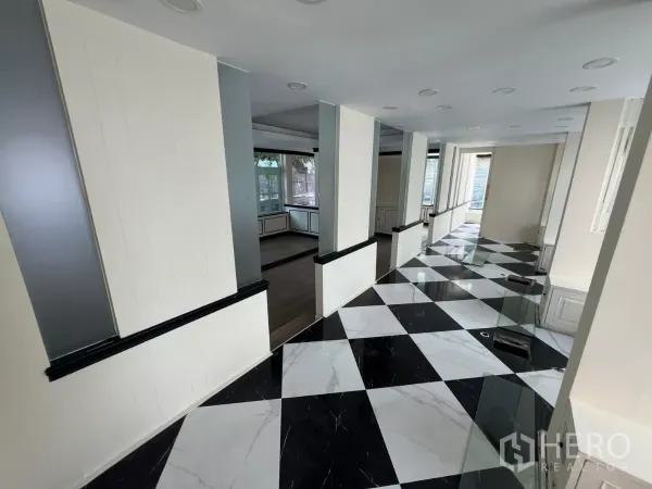 Retail Space for rent - Long corridor with columns and checkerboard tiles leading to a display area.