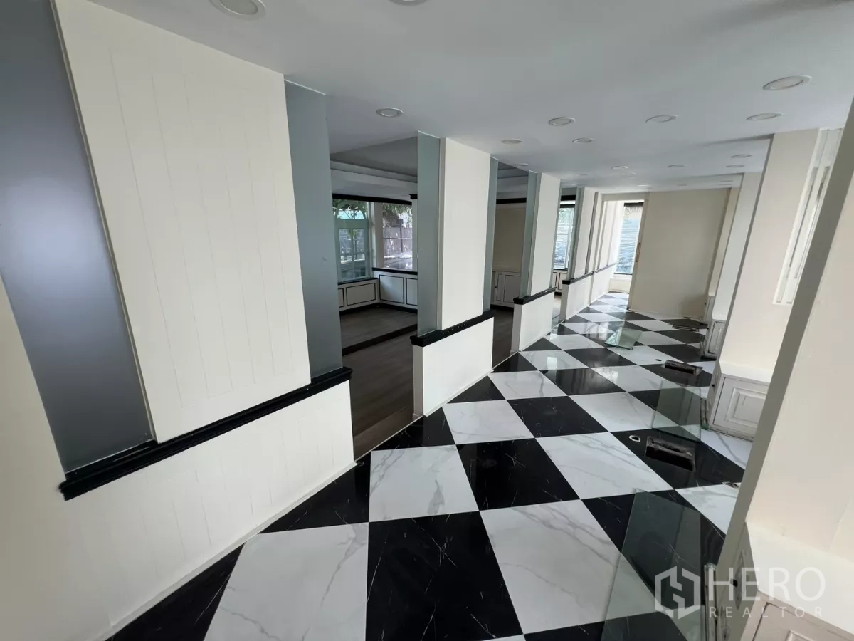 Retail Space for rent - Long corridor with columns and checkerboard tiles leading to a display area.