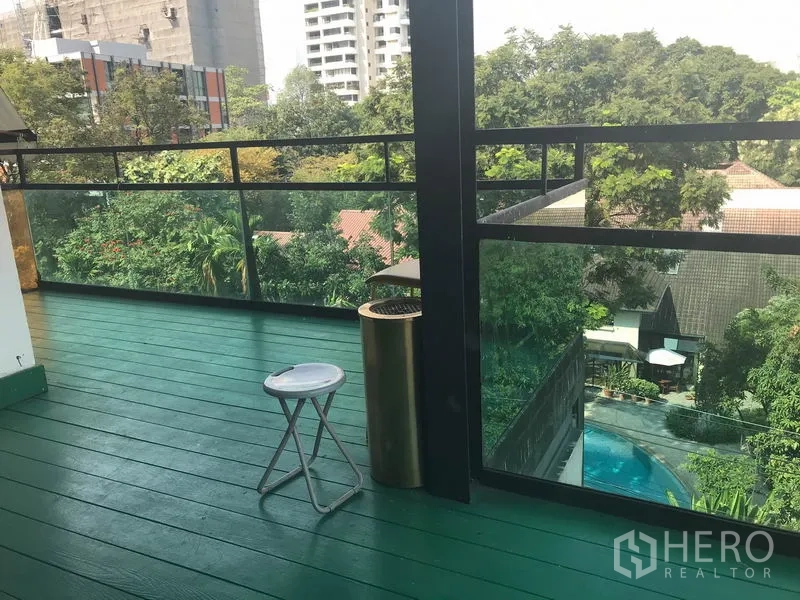 Retail Space for rent in Watthana, Bangkok - Spacious balcony terrace with green decking, glass railing and tree-lined city views.