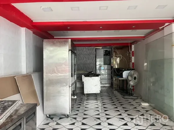 店屋 出租在Khlong Toei, Bangkok - 店屋一层内部，几何瓷砖地面与红色天花梁，配有不锈钢冷柜与操作台，适合餐饮改装。