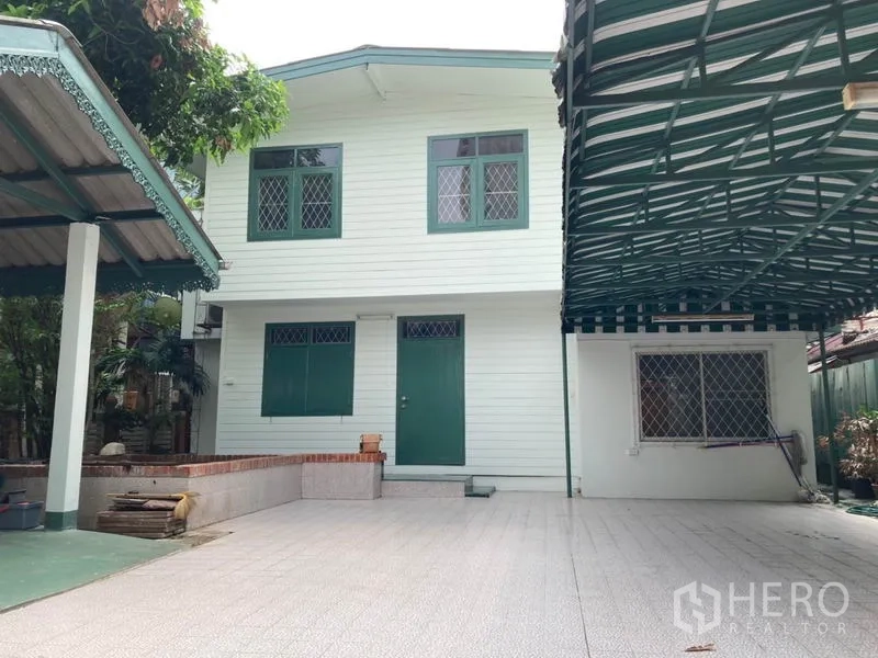 Detached House for rent in Sathon, Bangkok - Two-storey white detached house with green windows and a wide tiled courtyard.