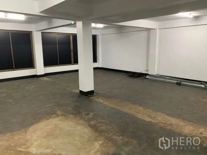Office Space for rent in Bang Rak, Bangkok - Spacious office area with a central column, ceiling strip lights and dark-tinted windows.