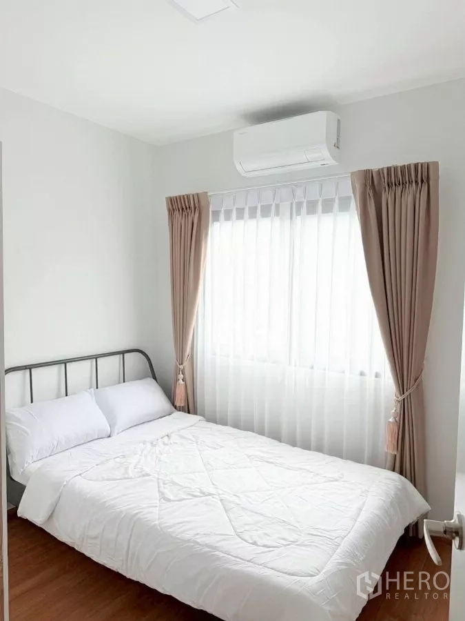 Townhouse for rent in Bang Phli, Samut Prakan - Second bedroom with metal bed frame, air conditioner and curtained window.