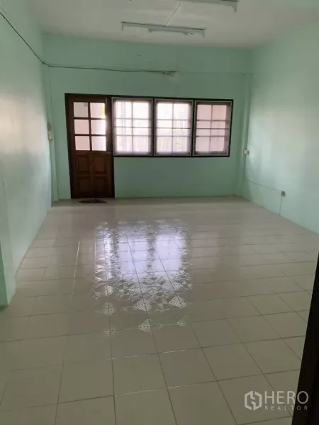 Shophouse for rent in Suan Luang, Bangkok - Bright tiled living or office space with a wood door and three-panel windows.