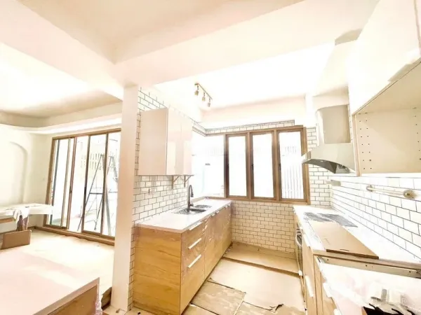Townhouse for rent in Khlong Toei, Bangkok - Sunlit kitchen with corner sink, subway tiles and sliding glass doors opening to a patio.