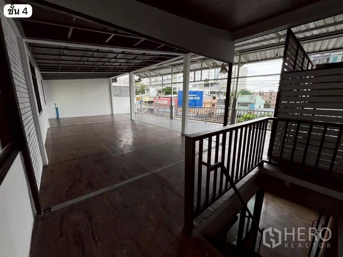 Shophouse for rent or sale in Khlong Toei, Bangkok - Covered rooftop terrace with wood flooring and staircase overlooking the city street.