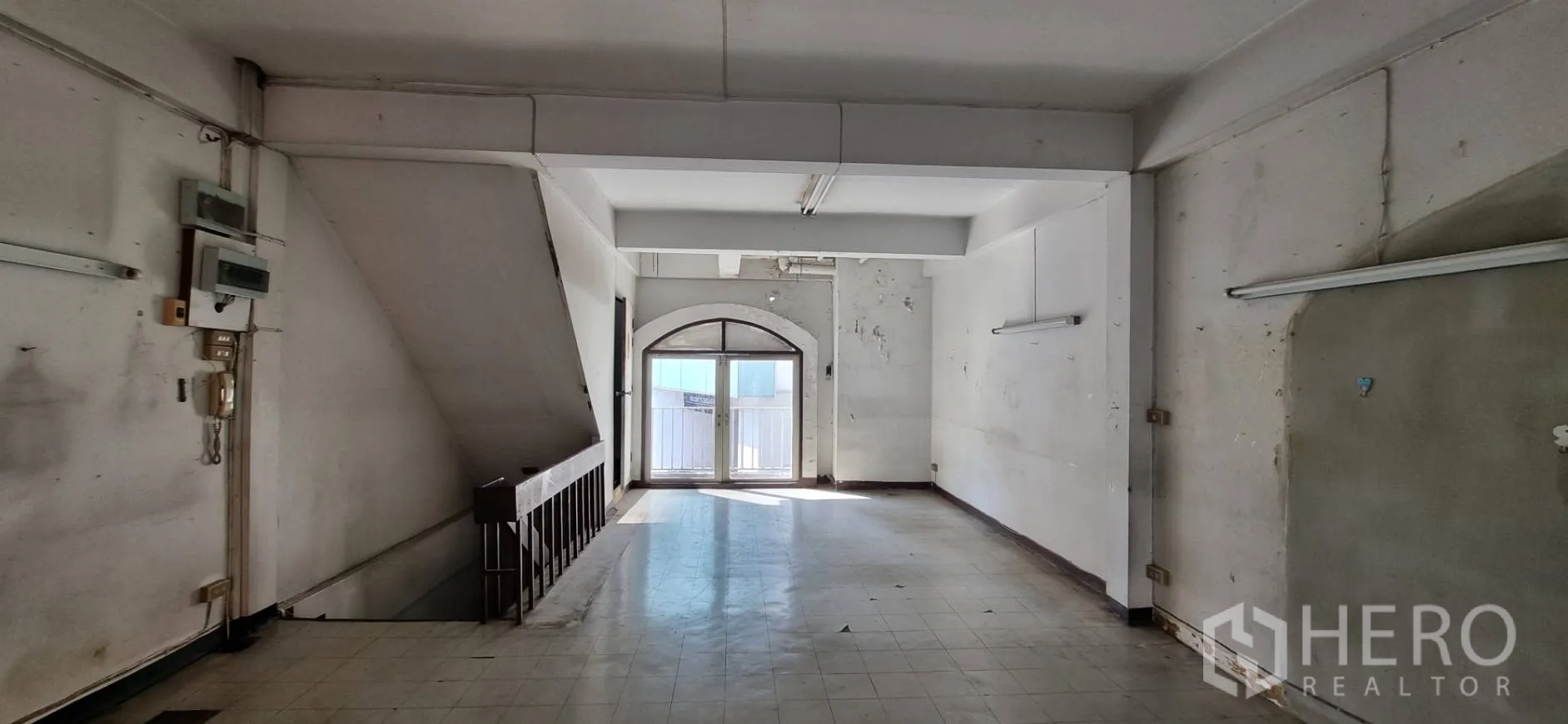 Shophouse for rent or sale in Bangkok - Corridor-like room with staircase balustrade and arched balcony doors.
