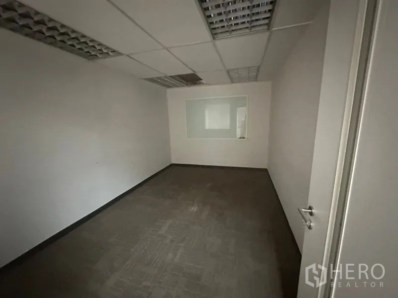 Office Space for rent in Khlong Toei, Bangkok - Private office with carpet tiles, suspended ceiling panels and an interior viewing window.