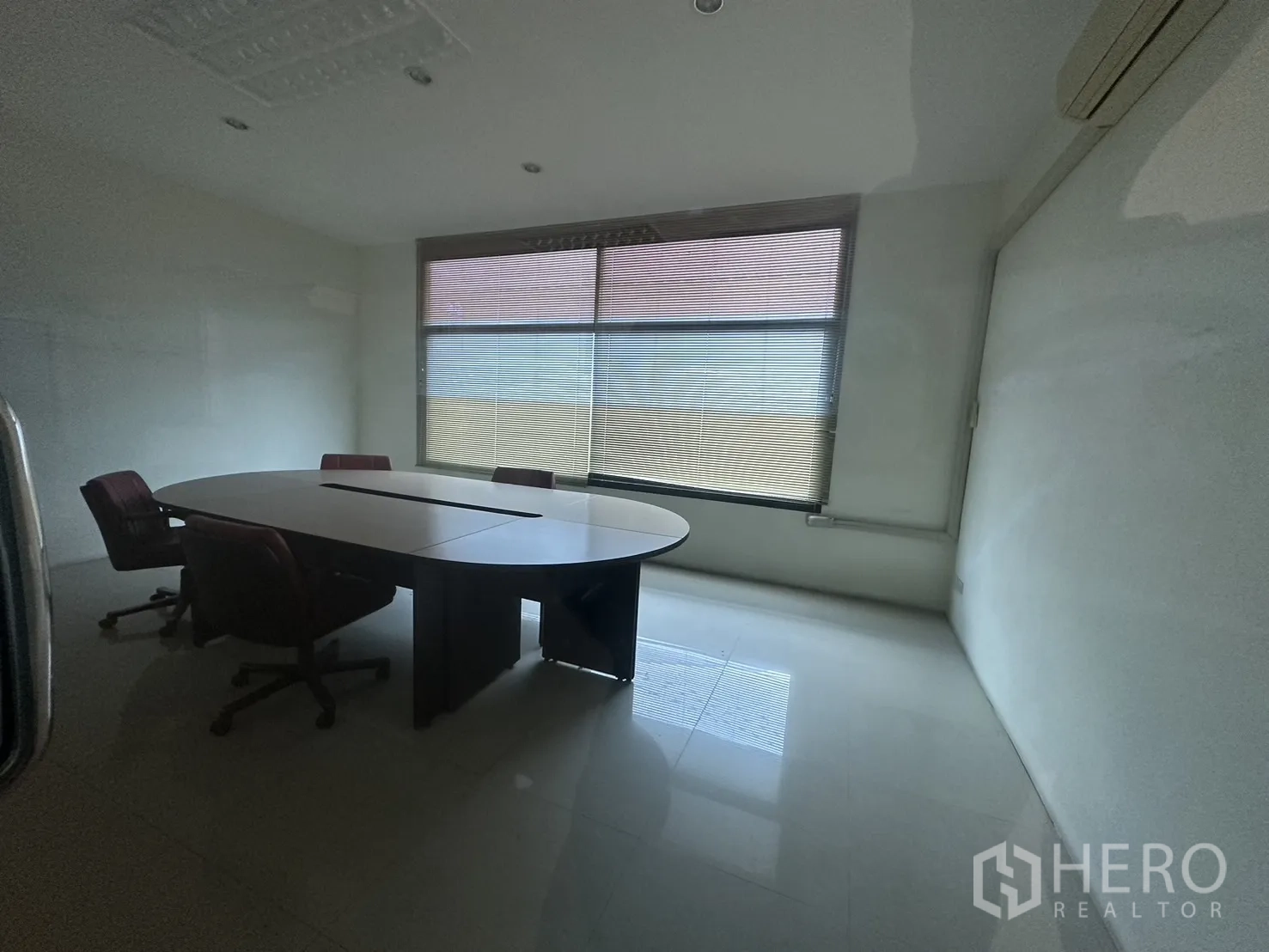 Factory for rent or sale in Prawet, Bangkok - Meeting room with oval conference table, chairs and a wide window with blinds.