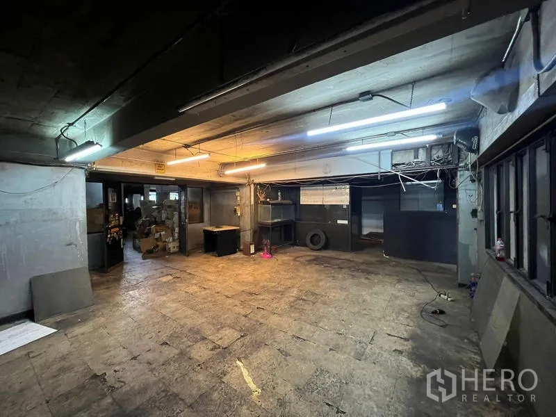 店屋 出租在Phra Khanong, Bangkok - 地下/后场工作区，荧光灯与外露管线。