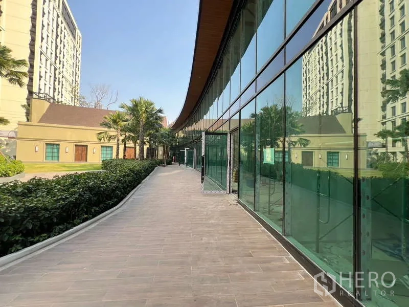Retail Space for rent in Khlong Toei, Bangkok - Pedestrian walkway lined with palm trees alongside full-height glass storefronts.