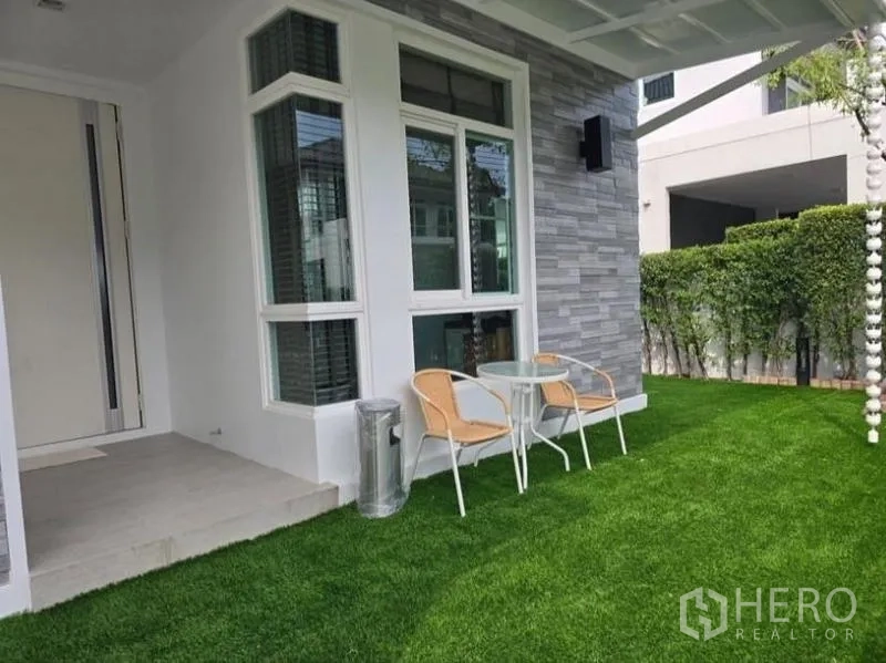 Detached House for rent - Front garden with small patio set beside bay window and stone-clad exterior wall.