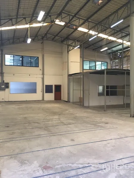 Warehouse for rent in Suan Luang, Bangkok - Spacious warehouse interior with high ceiling, steel trusses, concrete floor, and mezzanine offices with windows.