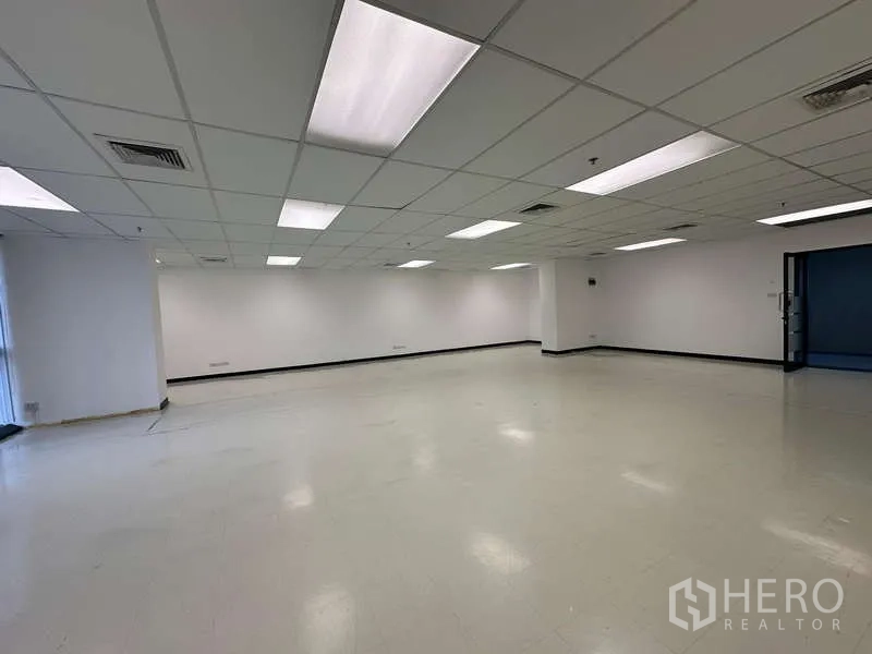 Office Space for rent - Spacious white-walled office floor with vinyl tile flooring, grid ceiling lighting and AC vents, ready for tenant fit-out near BTS Chitlom.