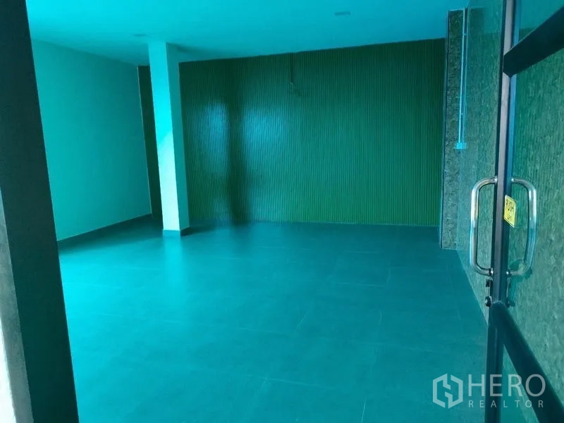 Factory for rent in Ban Phaeo, Samut Sakhon - Enclosed workspace with teal flooring and ribbed accent wall.