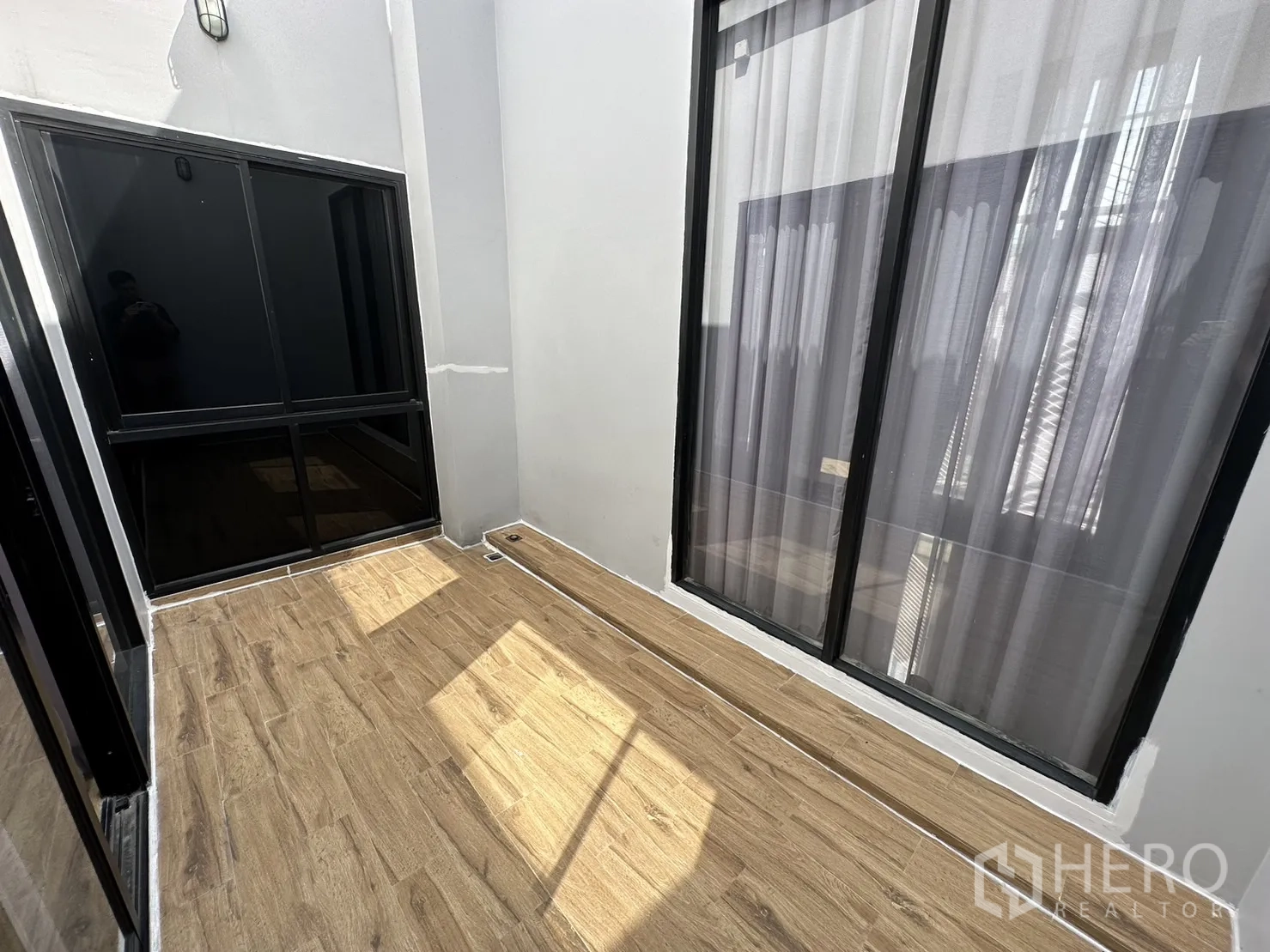 Home Office for rent or sale in Suan Luang, Bangkok - Compact lightwell terrace with wood tiles and black-framed glass doors.