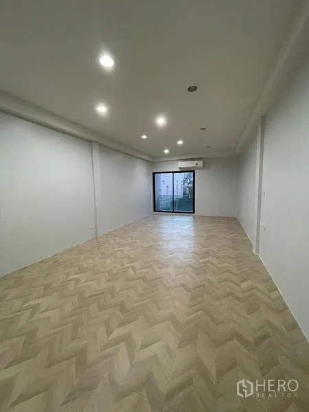 Home Office for rent in Chatuchak, Bangkok - Long open-plan room with recessed lights and balcony access through sliding door.