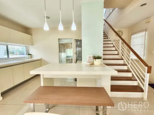 Detached House for rent in Prawet, Bangkok - Open-plan dining island with pendant lights beside the staircase leading to the kitchen.