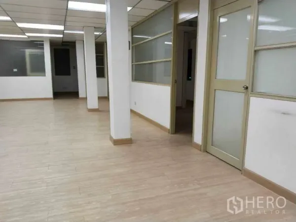 Office Space for rent in Bang Na, Bangkok - Large workspace with support columns and side rooms divided by sliding glass partitions.