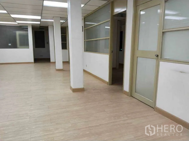 Office Space for rent in Bang Na, Bangkok - Large workspace with support columns and side rooms divided by sliding glass partitions.