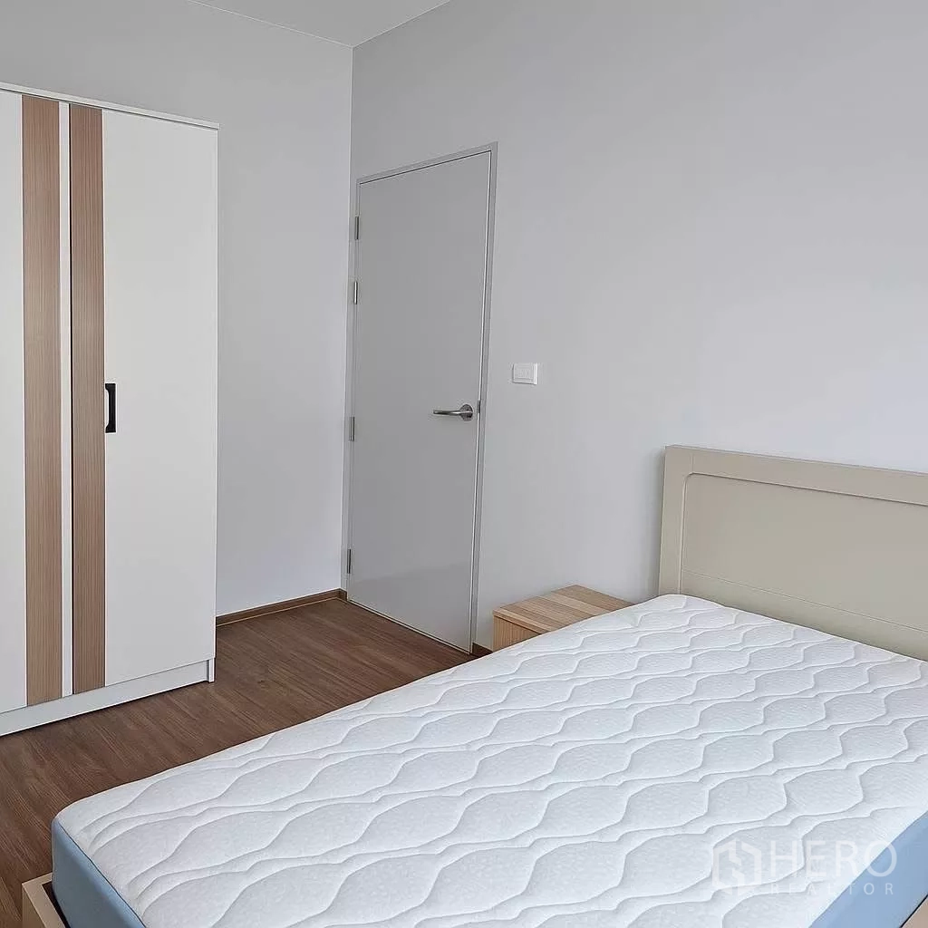 Townhouse for rent in Bang Phli, Samut Prakan - Second bedroom with wardrobe, bedside table and mattress on wood flooring.