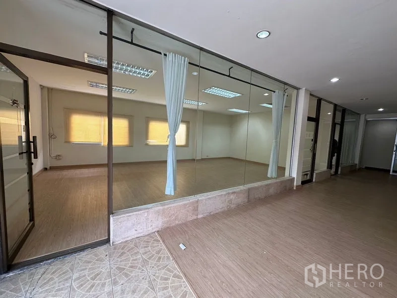 货栈 出租在Suan Luang, Bangkok - 走廊旁玻璃墙房间，带窗帘与筒灯，类似工作室。