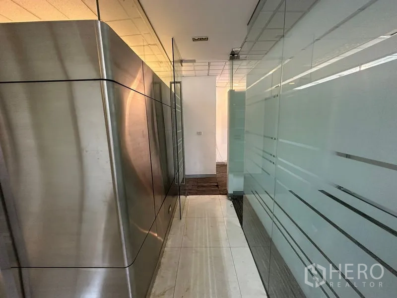 Office Space for rent - Hallway with frosted glass partitions and stainless-steel cladding leading to private offices.