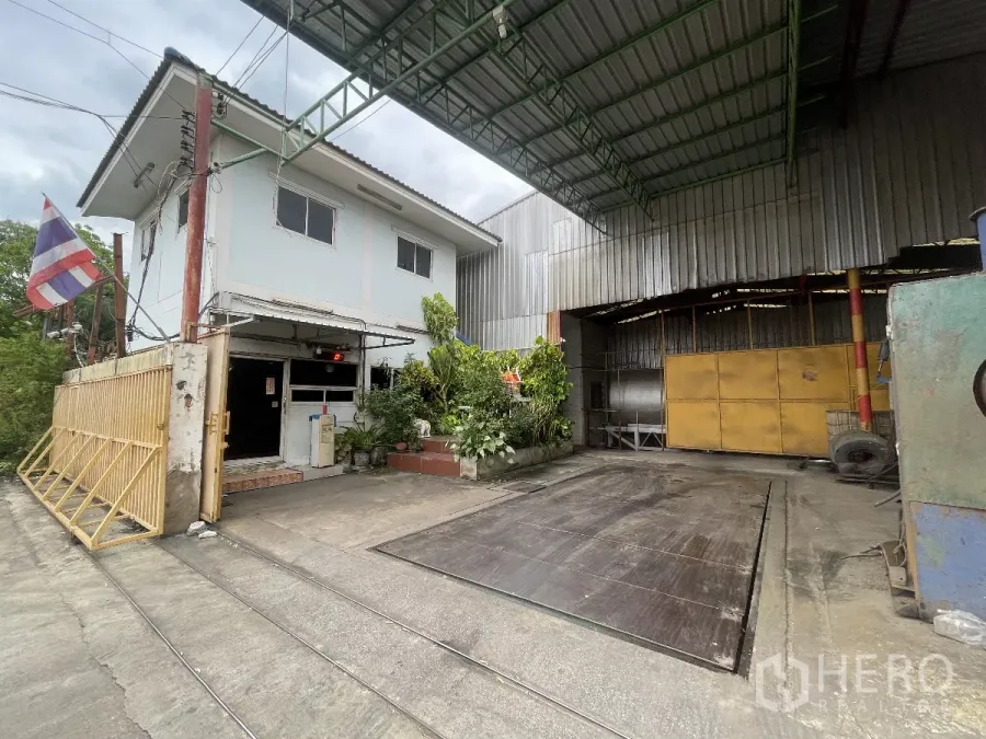 Factory for sale in Bang Bua Thong, Nonthaburi - Factory entrance with two-storey office, covered loading bay, and truck weighing scale in Bang Bua Thong.