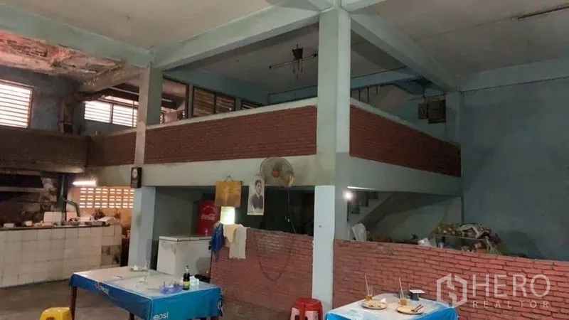 Shophouse for sale in Khlong Toei, Bangkok - Double-height interior with mezzanine platform and concrete columns suited for retail or dining.