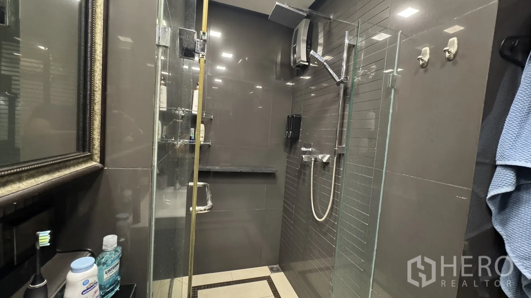 Condominium for rent or sale in Khlong Toei, Bangkok - Glass-enclosed shower with rainfall and handheld heads set against gray tiles.