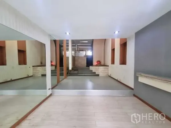 Shophouse for rent in Watthana, Bangkok - Split-level retail interior with steps, recessed wall niches, and bright lighting.
