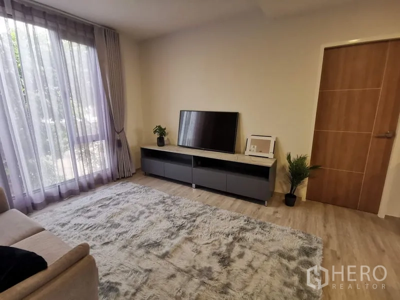 Townhouse for rent in Bang Phli, Samut Prakan - Upstairs family lounge with TV console, big rug and floor-to-ceiling sheer curtains.