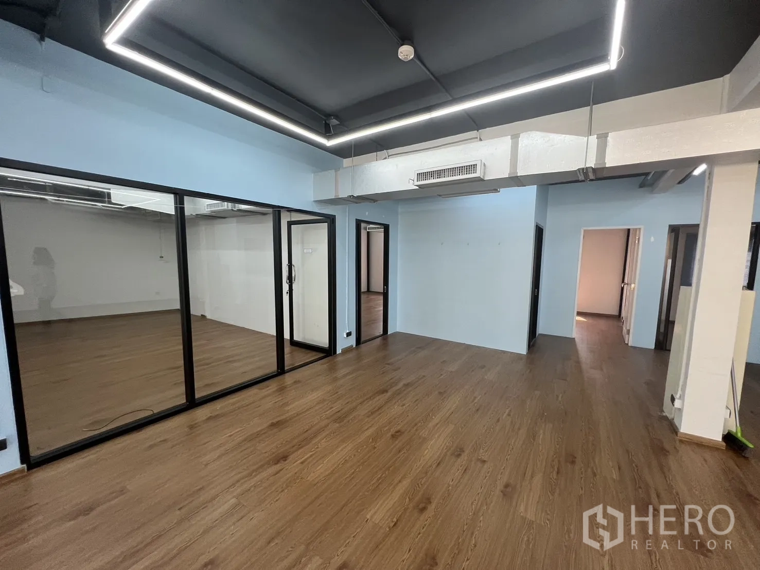 办公空间 出租在Khlong Toei, Bangkok - 办公室一角，玻璃会议室门、外露天花与风管、木纹地板清晰可见。