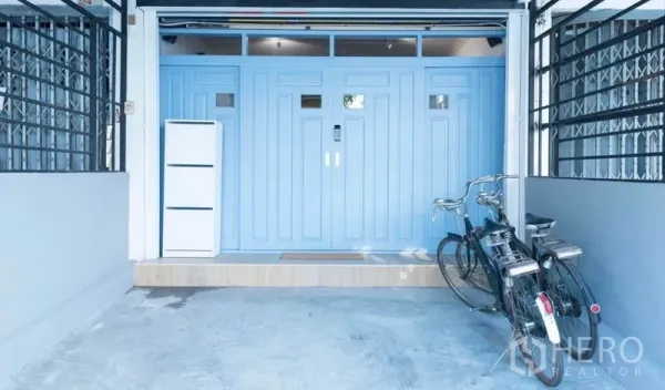 Townhouse for rent in Khlong Toei, Bangkok - Covered carport with pastel blue security door and two bicycles at the townhouse entrance.