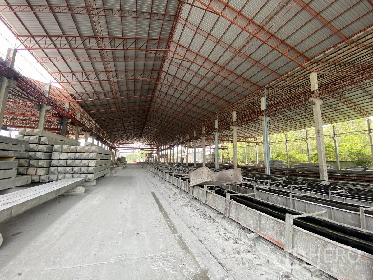 Factory for sale in Chon Buri - Long aisle through a precast plant with molds on both sides and finished products stacked.