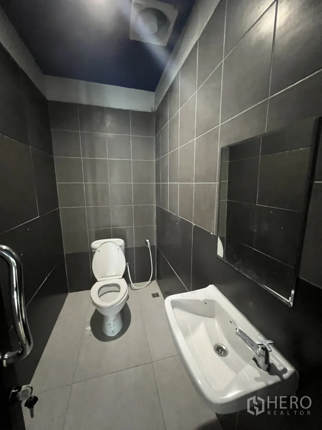 Office Space for rent in Watthana, Bangkok - Restroom with dark tiled walls, toilet, sink and mirror.