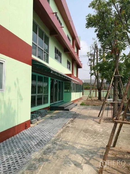 工厂 出租在Mueang Samut Sakhon, Samut Sakhon - 厂房侧立面，带遮阳步道、窗户及新植树木。