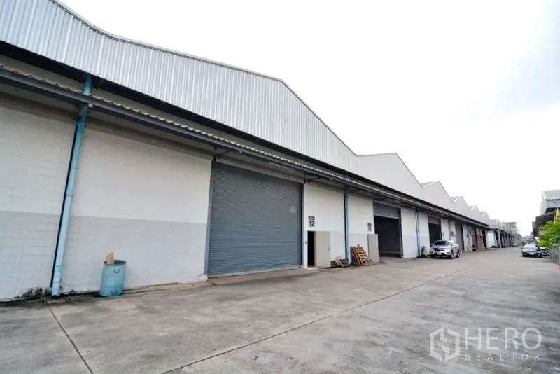 Warehouse for rent in Phra Pradaeng, Samut Prakan - Warehouse exterior row with roller shutter doors and a wide driveway for trucks.