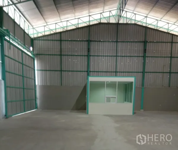 Warehouse for rent in Bang Bua Thong, Nonthaburi - Spacious warehouse interior with high steel truss roof and a glass-partitioned office.