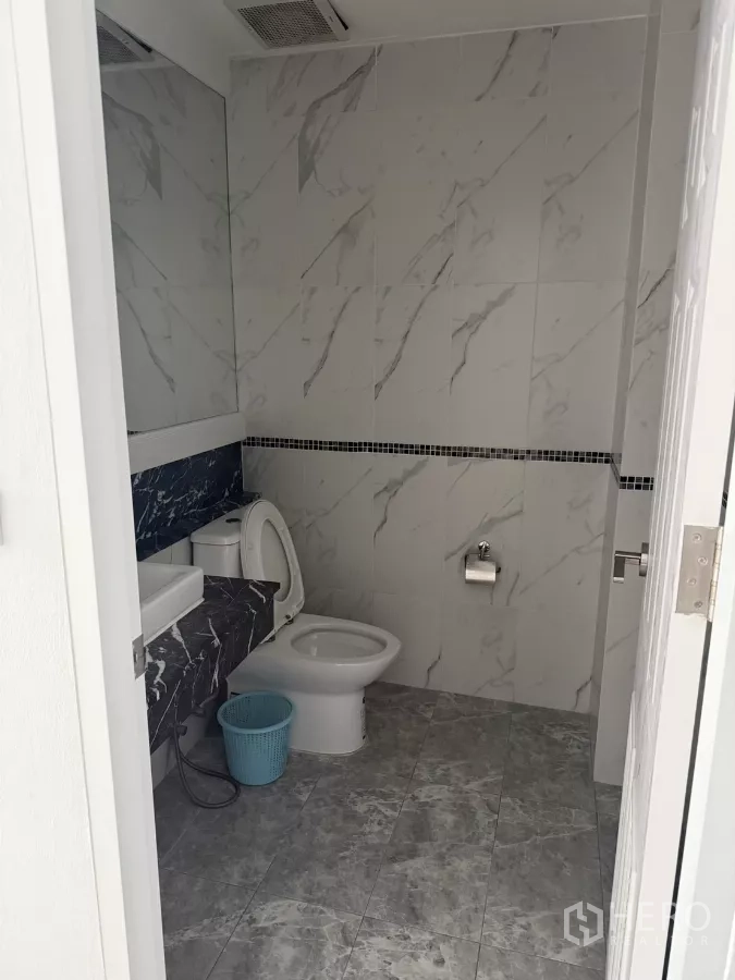 Shophouse for rent - Second bathroom with marble-pattern tiles, vanity, and toilet.